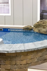 Modern backyard pool with stone coping, water features, and outdoor patio design