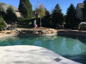 Custom backyard pool with stone waterfall feature and sandy beach entry in Cincinnati