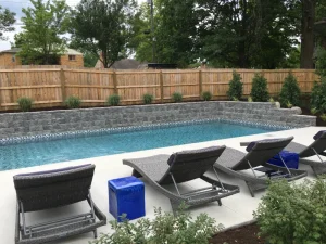 Modern backyard pool with lounge chairs and stone retaining wall in Cincinnati