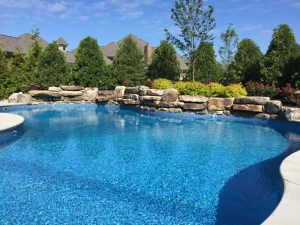 Custom backyard pool with stone waterfall and landscaping in Cincinnati residential outdoor living space