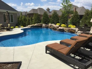 Luxury backyard pool with lounge chairs, rock waterfall, and outdoor patio furniture