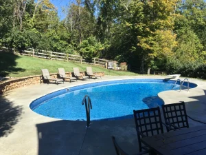 Blue above ground pool with concrete patio and outdoor furniture in Cincinnati backyard