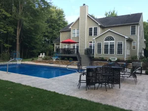 Luxury backyard with in-ground pool, patio furniture, and two-story home with deck