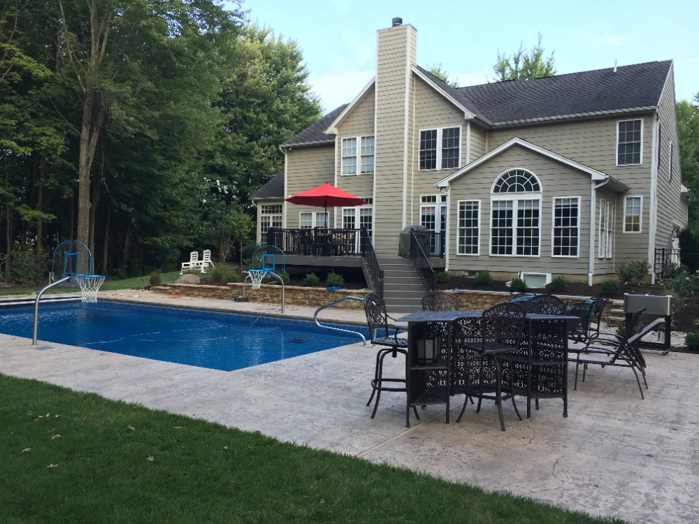 Luxury backyard with in-ground pool, patio furniture, and two-story home with deck
