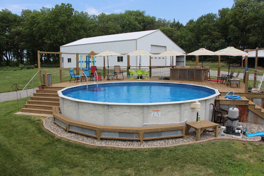 Above ground pool with wooden deck, patio furniture, and backyard outdoor living setup