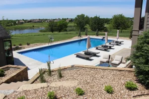 Modern backyard pool with lounge chairs and patio furniture overlooking landscaped grounds