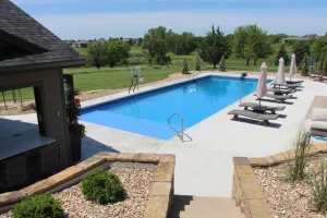 Luxury backyard pool with concrete patio, lounge chairs, and outdoor living space