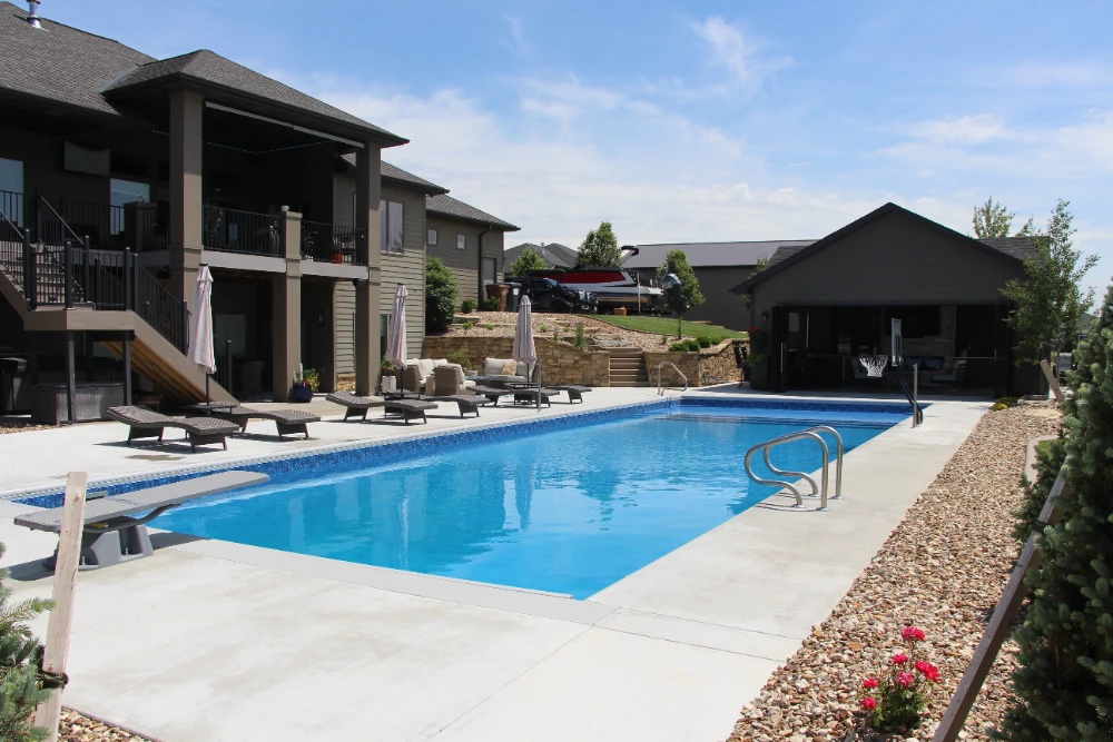 Luxury backyard pool with lounge chairs, patio furniture, and modern outdoor living space