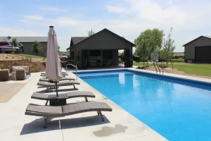 Luxury backyard pool with loungers, umbrella, and modern outdoor patio pavilion