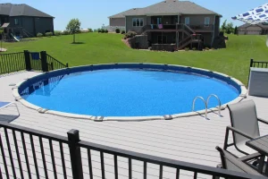 Large above ground pool with gray composite deck and black safety railing in Cincinnati backyard