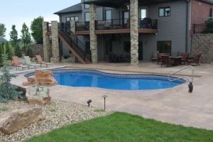 Luxury backyard pool with stone patio, outdoor furniture, and modern home installation