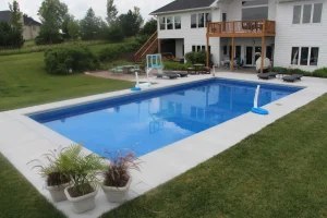Modern backyard pool installation with wooden deck and outdoor patio furniture near Cincinnati
