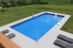 Modern rectangular backyard pool with concrete patio and lounge chairs