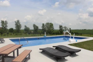 Modern backyard pool with lounge chairs and patio furniture overlooking rural landscape